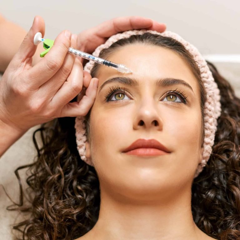 Crop anonymous beautician injecting charming female client with anti age filler during skin care procedure in modern light beauty salon