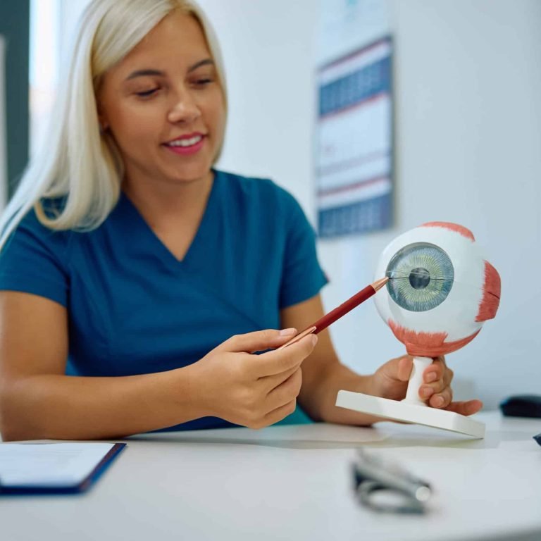 Happy female optometrist using anatomical model of human eye at the clinic.